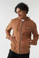 Campera marrón de felpa con capucha y cordón ajustable, lettering estampado en la espalda, bolsillo en la manga, puños y logo en grifa de goma.