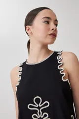 Top negro sin mangas con bordado blanco en el frente y contorno.