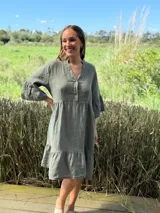 Vestido midi color verde oliva, de lino, con cuello mao, escote con botones de nácar, mangas 3/4 con volados y ruedo con volados.