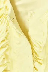 Chaqueta corta color amarillo pastel con textura de volantes, cuello redondo, manga larga y cierre frontal con botón a presión oculto.
