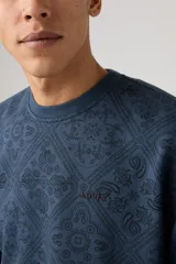 Sweater azul con estampado de cachemira en toda la prenda, cuello redondo y corte relajado.