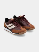 Zapatillas deportivas de cuero color marrón y beige con cordones burdeos y suela blanca.