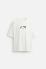 Camiseta blanca de corte relajado, cuello redondo y manga corta. Presenta un estampado de gráficos y textos combinados a contraste en la parte delantera y trasera.