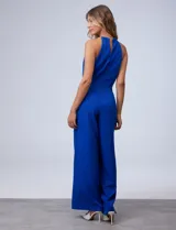 Enterito de crepe azul, marca Donna Ricco, con cuello halter con collar dorado, escote central, bolsillos laterales y cierre invisible en la espalda.