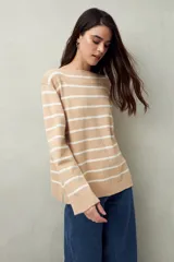 Sweater de punto a rayas horizontales color beige y blanco, con cuello bote y corte holgado.