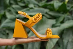 Sandalias de cuero color mostaza con textura de piel de serpiente, taco geométrico y detalle de cadena gruesa al tono.