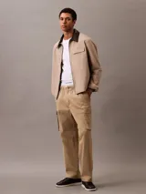 Pantalón cargo color beige de algodón orgánico elástico, con cintura elástica y corte recto. Presenta bolsillos laterales, traseros y tipo cargo en las piernas.