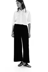 Pantalón negro de punto con textura, corte holgado, tiro alto, piernas rectas, elástico revestido en la cintura y cordón para ajustar.