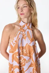 Vestido corto con estampado floral en tonos beige y rojo, con cuello halter y corte evasé.