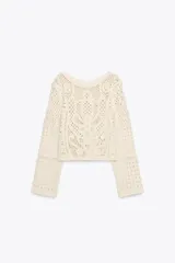 Top color crudo de tejido crochet calado, con cuello redondo y mangas largas acampanadas.