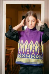 Chaleco de punto morado con cuello alto y diseño geométrico amarillo y azul.