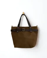 Bolso tipo tote de gamuza color verde oliva con asas de cuero marrón y detalle de cinturón decorativo con hebilla.
