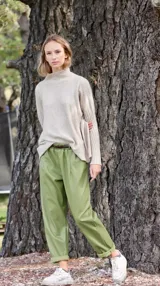Pantalón babucha verde de cuerina con bolsillos laterales y cinturón fino marrón.