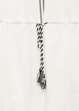 Vestido blanco de algodón con bordados negros en cuello, mangas y cintura. Tiene mangas 3/4 con puños elásticos, corte evasé y cintura elástica con lazo.