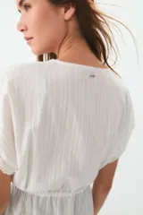 Túnica blanca de ratier de algodón con detalles de puntilla en el escote y lazo para ajustar en la cintura.