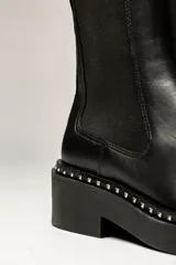 Botas Chelsea negras de cuero, con plataforma track y detalle de tachas plateadas en la suela.