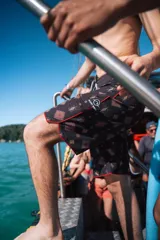 Short de baño negro con estampado geométrico en tonos marrones y contorno rojo.