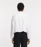 Campera blanca de viscolino, modelo globo, con cuello camisero, manga larga, cierre delantero y bolsillos fake.