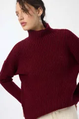Buzo tejido acanalado color burdeos, con cuello alto y manga caída, de corte holgado.