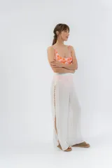 Pantalón blanco de gasa liviana con cintura elástica y aberturas laterales con detalle de pompones.