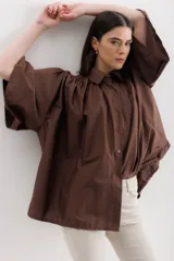 Camisa celeste de algodón con corte amplio, cuello camisero y mangas largas con puños abullonados.