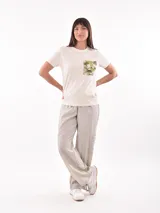 Remera color crudo de corte recto, con cuello redondo y bolsillo en el pecho con estampado camuflado en tonos verdes y marrones.