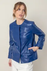 Campera azul de cuero ovino italiano, con cuello redondo, cierre frontal con broches ocultos, bolsillos laterales y detalle de capitoneado en puños y bolsillos.