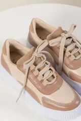 Zapatilla de cuero vacuno en tonos beige y verde, con suela blanca y detalles de diseño moderno.