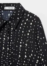 Camisa de tejido fluido con diseño recto, cuello camisero, y manga larga abotonada, con cierre de botones en la parte delantera.