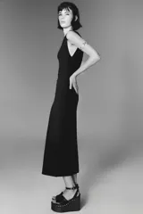 Vestido midi negro de punto, con escote asimétrico, manga sisa y aplique dorado en el hombro.