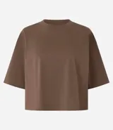 Blusa color beige, cropped y de corte amplio, confeccionada en tejido de media malla, con cuello redondo y mangas cortas.