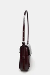 Bolso de hombro color crema con efecto acharolado, solapa con cierre imantado y asa ajustable.