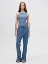 Pantalón de jean azul de tiro alto y corte oxford con apliques metálicos en bolsillos y laterales.