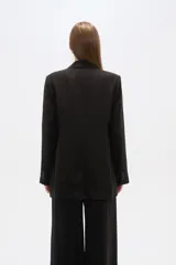Blazer negro de corte holgado, con cuello solapa, cierre con doble botón y bolsillos laterales con solapa.