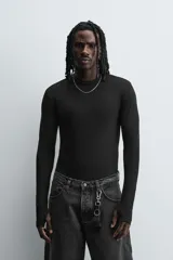 Camiseta de manga larga color crudo, corte ajustado y cuello redondo. Tiene aberturas en los puños y efecto lavado.