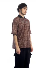 Remera deportiva marrón con cuello polo negro, cierre parcial con cremallera, mangas cortas y estampado con letras.