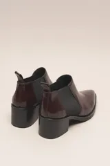 Botín negro de cuero vacuno con acabado charol, estilo botín Chelsea con puntera fina y elástico lateral. Posee un taco ancho y bajo de 5.5 cm.