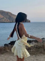 Vestido corto color amarillo pálido con cuello halter y falda con volados.