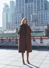Abrigo marrón de lana con doble botonadura, cuello con solapa de muesca, dos bolsillos laterales, hombros caídos, diseño oversize y largo, con forro interior.