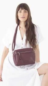 Bandolera morral negra de símil cuero con cierre principal, bolsillos interiores, bolsillo frontal y posterior con cierres, y bolsillos laterales. Incluye correa extensible.