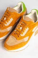 Zapatillas deportivas color mostaza con detalles en beige, verde y blanco.
