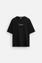 Camiseta negra de corte holgado con cuello redondo y mangas cortas. Estampado frontal con la frase "Unfolding Dreams" en letras blancas.