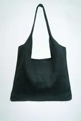 Bolso negro tipo tote bag con textura acanalada y asas de hombro.