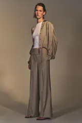 Pantalón de tiro alto color beige, con bolsillos delanteros y falsos bolsillos traseros. Pierna ancha y cierre frontal con ganchos metálicos y botones.