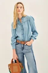 Camisa celeste de tencel con calce recto, cuello redondo con volados, canesú en delantero y espalda, y mangas largas terminadas en puño con botón snap.