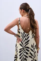 Vestido largo color crudo con estampado de hojas negras, de corte suelto y breteles finos.