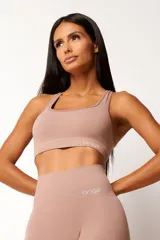 Top deportivo color rosa nude, con breteles anchos y espalda tipo nadador. Confeccionado con tecnología seamless y textura acanalada. Incluye forro y apertura para almohadillas.