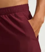 Bermuda deportiva color bordó, confeccionada en poliéster, con cintura elástica, cordón interno ajustable y short de compresión incorporado.