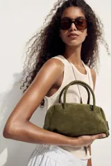 Bolso tipo bowling color verde oliva, confeccionado en cuero. Tiene doble asa corta y cierre superior con doble cremallera.