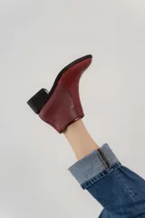 Bota corta de cuero color bordó con diseño de escamas en la parte delantera, cierre lateral y taco cuadrado.